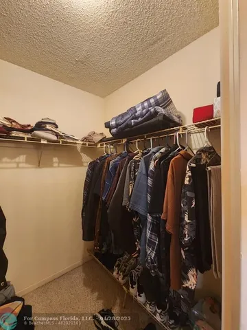 a view of walk in closet with clothes and shoes