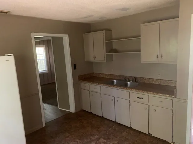 a kitchen with granite countertop white cabinets and refrigerator