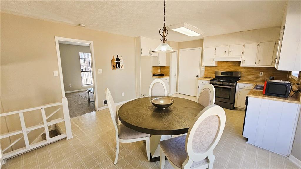 337 Independence Drive Jonesboro, GA 30238 - Photo 9 of 41 a kitchen with stainless steel appliances granite countertop a stove a refrigerator and a dining table with wooden floor