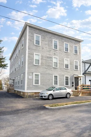 a front view of a building with lot of cars and trees