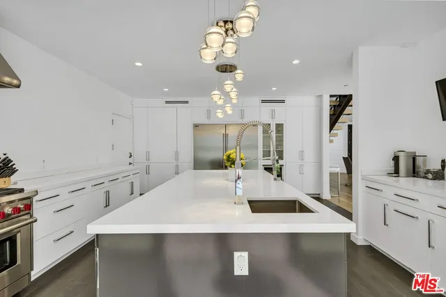 a large kitchen with a sink dishwasher a stove and white cabinets with wooden floor