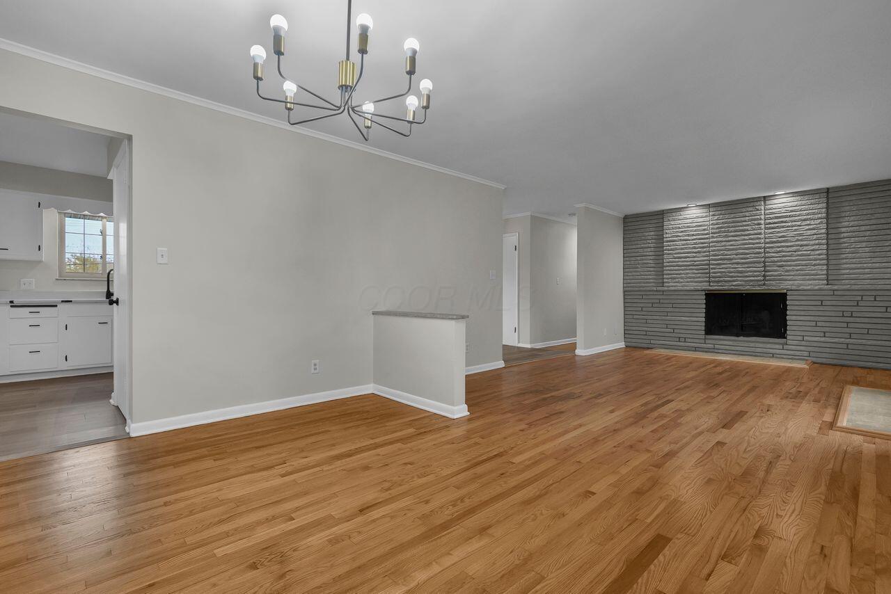 1535 Kenwick Road Columbus, OH 43209 - Photo 5 of 26 Dining area with chandelier, hardwood floors, and open flow to living room and fireplace.