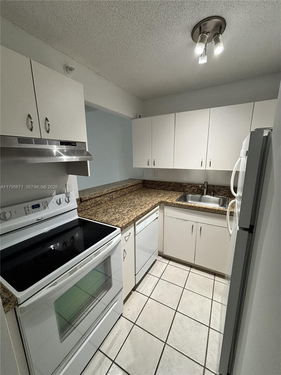 126 Southwest 17th Road, Unit 505 Miami, FL 33129 - Photo 15 of 27 a kitchen with granite countertop a stove sink and cabinets