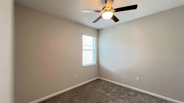 an empty room with a window and a fan