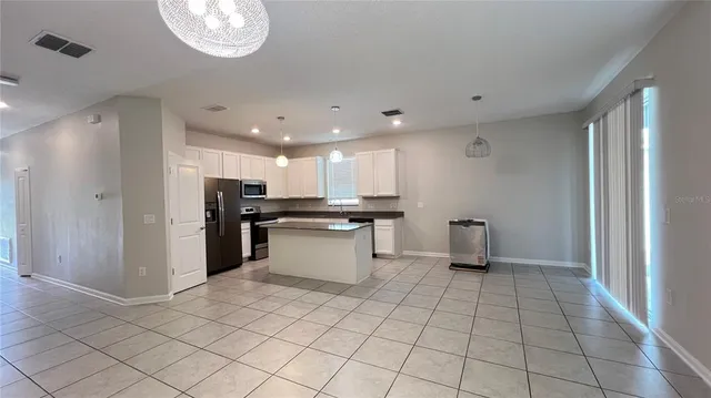 a kitchen with stainless steel appliances kitchen island granite countertop a refrigerator and a sink