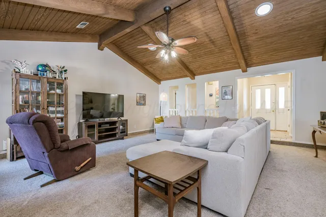 a living room with furniture a ceiling fan and a flat screen tv