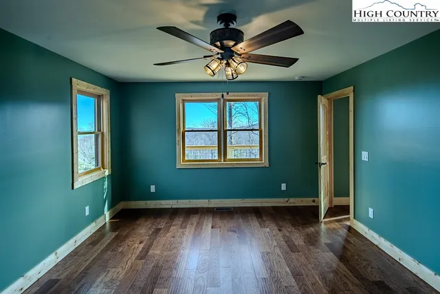an empty room with wooden floor closet and windows