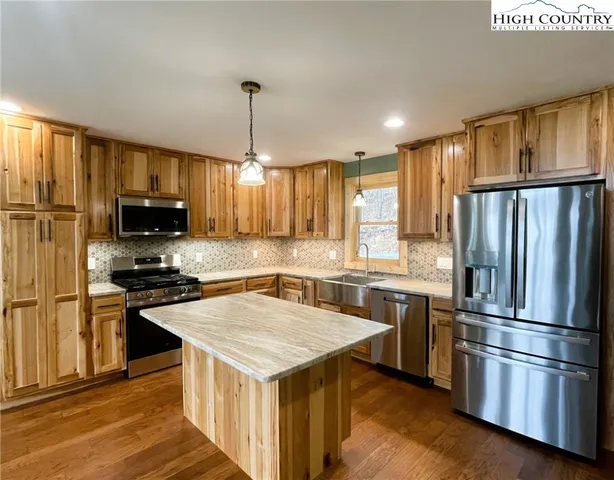 a kitchen with a center island wooden floor and stainless steel appliances