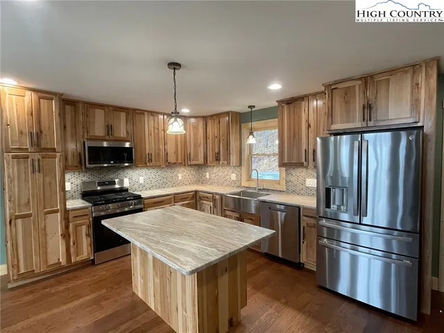 a kitchen with kitchen island granite countertop stainless steel appliances and wooden cabinets