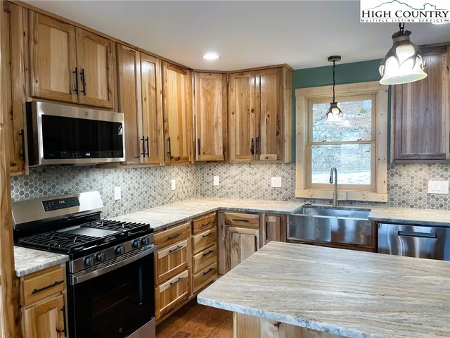 a kitchen with stainless steel appliances granite countertop a stove a sink and a microwave