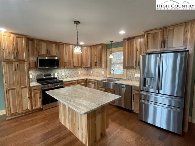 a kitchen with a refrigerator a microwave oven and a sink with wooden floor