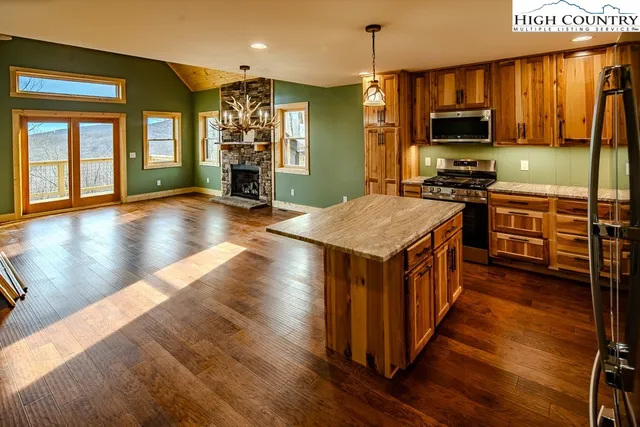 a kitchen with stainless steel appliances granite countertop a refrigerator a stove top oven a sink dishwasher and wooden cabinets with wooden floor