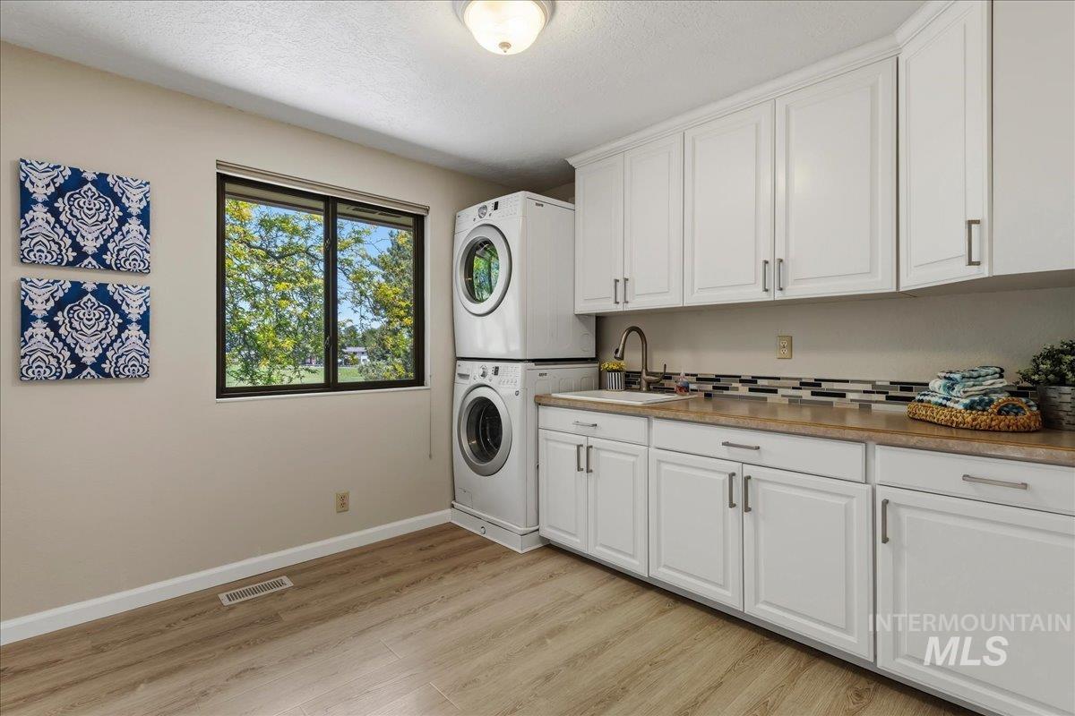 599 Pebble Beach Way Eagle, ID 83616 - Photo 26 of 44 Dedicated laundry area featuring wood-finish flooring, white cabinetry with brushed nickel hardware, and a utility sink