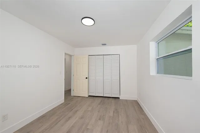 a view of an empty room with wooden floor and closet
