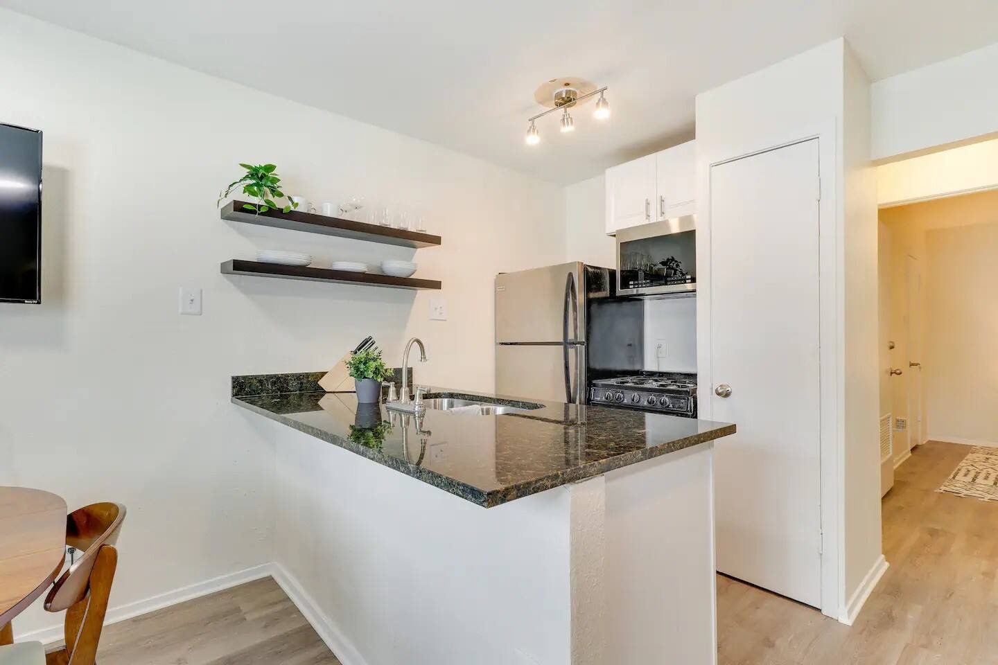 2401 Manor Road, Unit 129 Austin, TX 78722 - Photo 14 of 21 Kitchen with a peninsula, dark stone countertops, open shelves, light wood finished floors, and stainless steel appliances