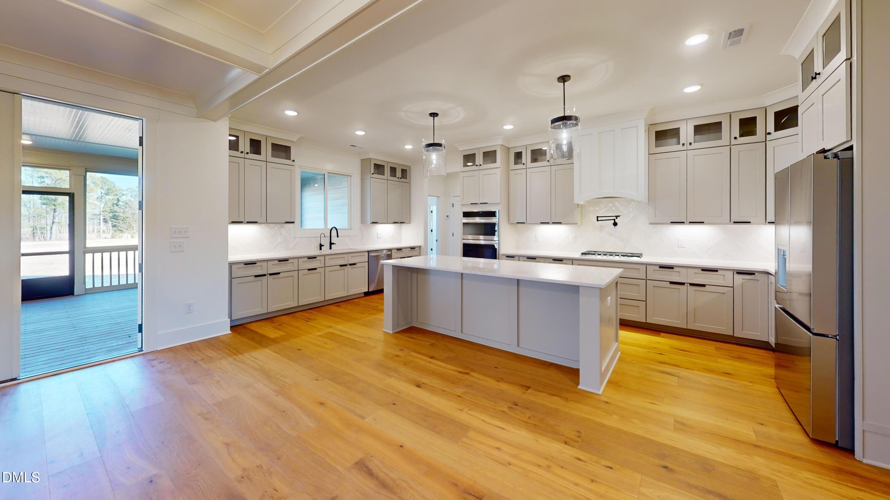 5008 Hopkins Chapel Road Zebulon, NC 27597 - Photo 18 of 32 a large kitchen with stainless steel appliances granite countertop a stove cabinets and wooden floor