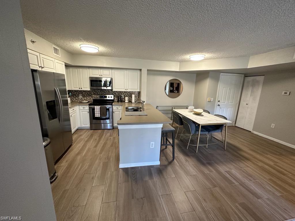 a living room with stainless steel appliances kitchen island granite countertop furniture a refrigerator a sink a stove a microwave and dining table