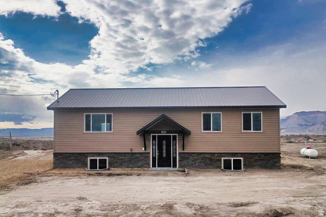 Two-story residence featuring light brown horizontal siding and a dark gray metal roof