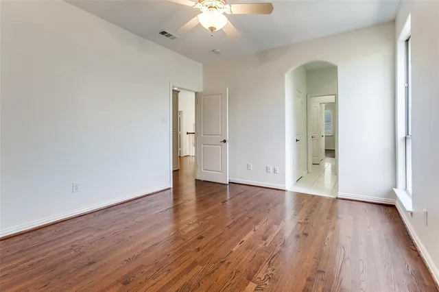 an empty room with wooden floor and a ceiling fan