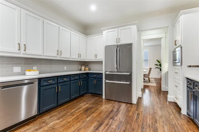 a kitchen with stainless steel appliances granite countertop a refrigerator oven a sink dishwasher and white cabinets with wooden floor