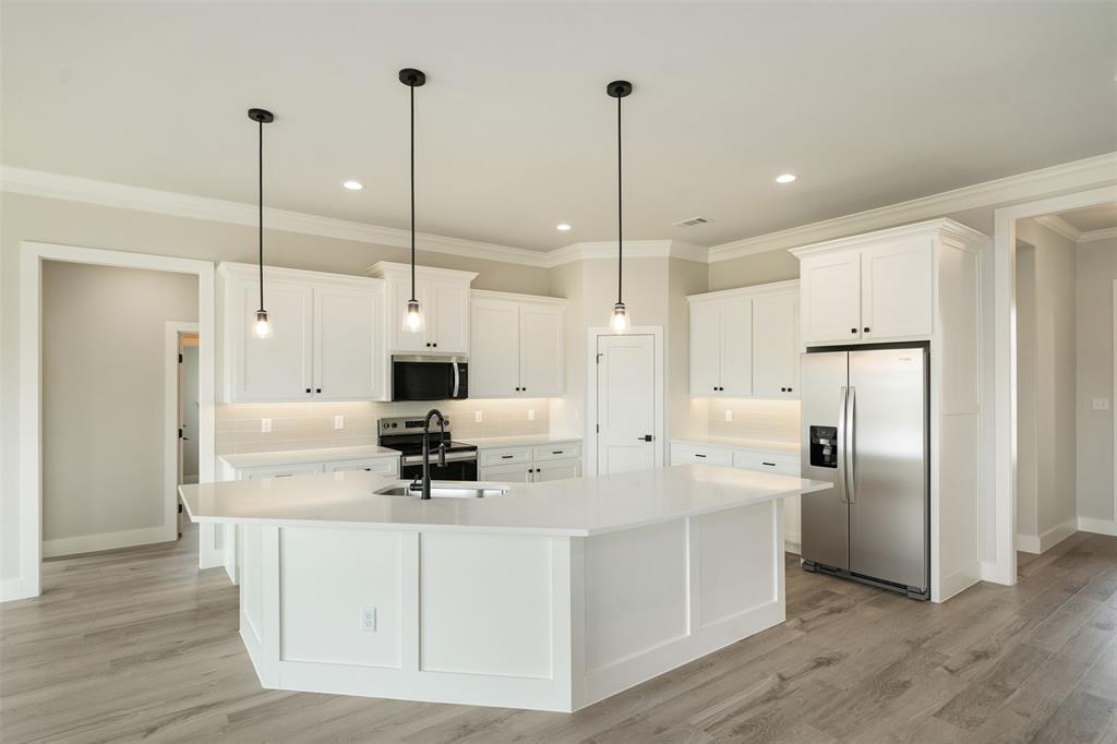 509 Limestone Circle Mabank, TX 75147 - Photo 8 of 36 a kitchen with stainless steel appliances kitchen island granite countertop a refrigerator a sink and white cabinets