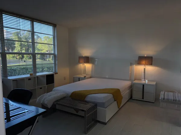 a spacious bedroom with a bed window and lamp