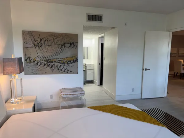 a bedroom with a bed and a lamp on dresser