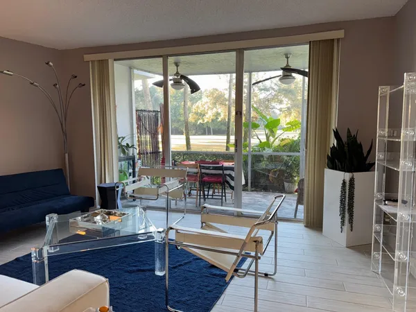 a living room with furniture a flat screen tv and a floor to ceiling window
