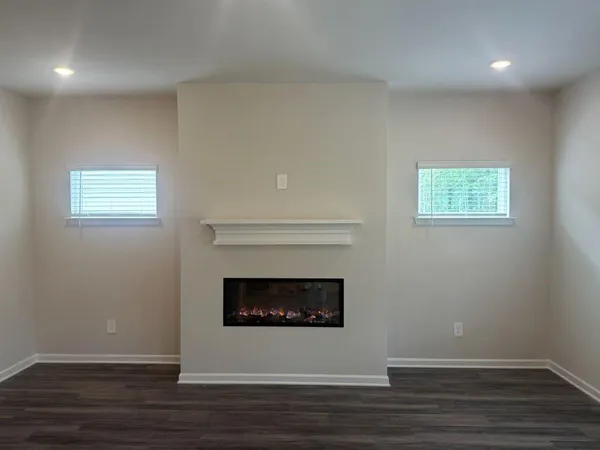 a view of an empty room with wooden floor and a fireplace