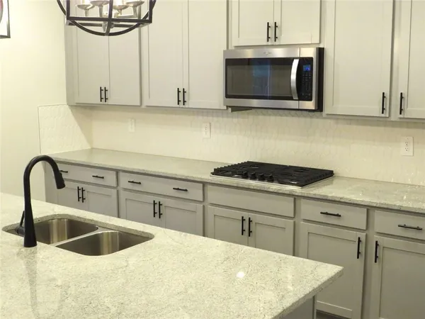 a kitchen with stainless steel appliances granite countertop a sink a microwave and cabinets