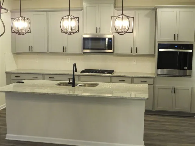 a kitchen with stainless steel appliances granite countertop a sink a microwave oven a stove and white cabinets