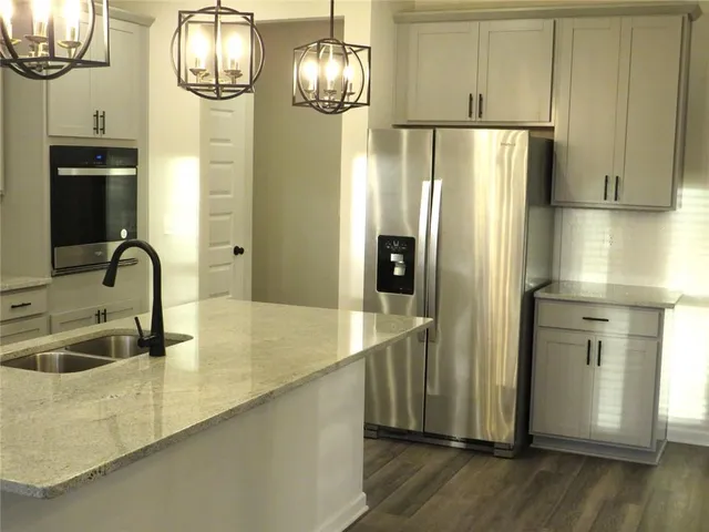 a kitchen with stainless steel appliances granite countertop a refrigerator a stove and a wooden floors