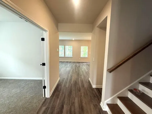 a view of a hallway with wooden floor and staircase