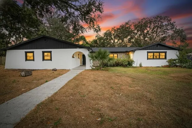 a view of house with yard and trees in the background