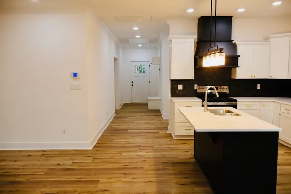 a kitchen with stainless steel appliances granite countertop a refrigerator a sink a stove and wooden floor