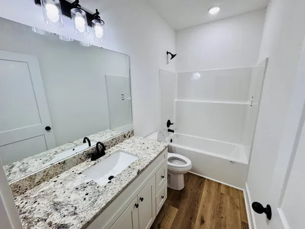 a bathroom with a granite countertop toilet sink and mirror