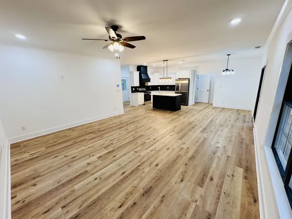 a large kitchen with a refrigerator a stove top oven a sink dishwasher and a wooden floor