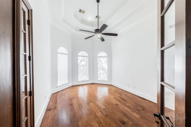 a view of an empty room with a window and wooden floor