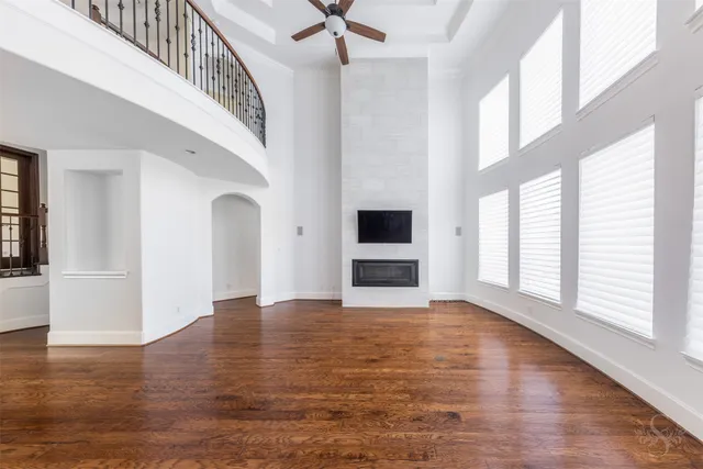 a view of wooden floor fire place and windows in an empty room