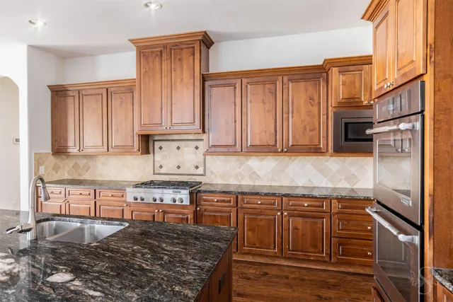 a kitchen with stainless steel appliances granite countertop a stove a sink and a microwave