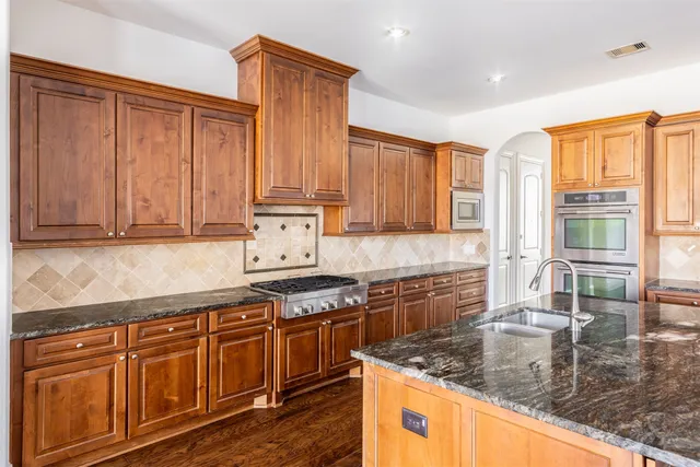 a kitchen with granite countertop cabinets stainless steel appliances and a window