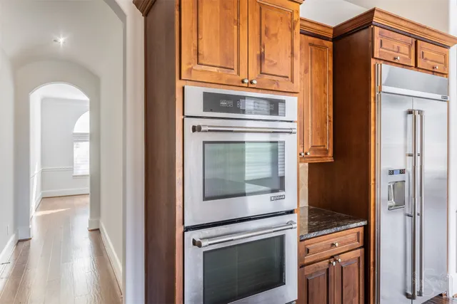 an empty room with wooden floor chandelier and windows
