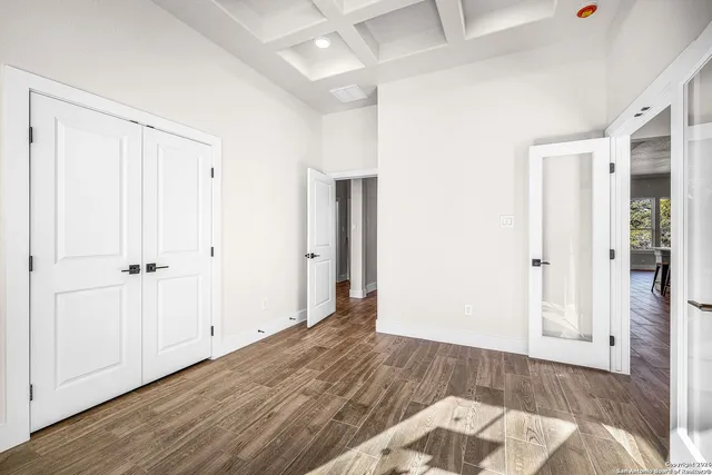 an empty room with wooden floor & closet area