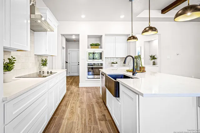 a large kitchen with kitchen island a large counter space a sink appliances and cabinets