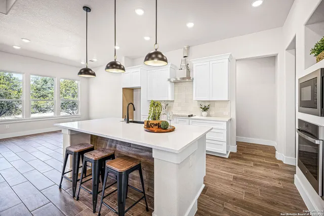 a kitchen with stainless steel appliances a table chairs and wooden floor