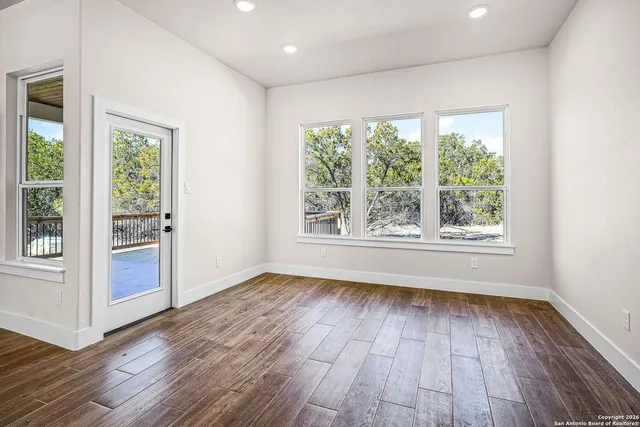a view of an empty room with wooden floor and a window