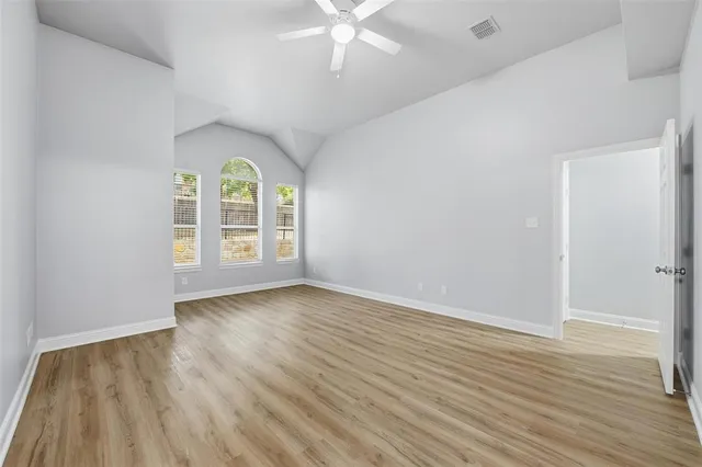 an empty room with wooden floor chandelier fan and windows