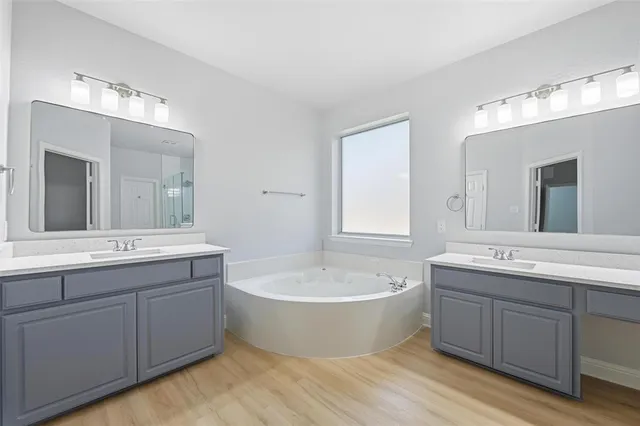 a spacious bathroom with a double vanity sink mirror and bathtub
