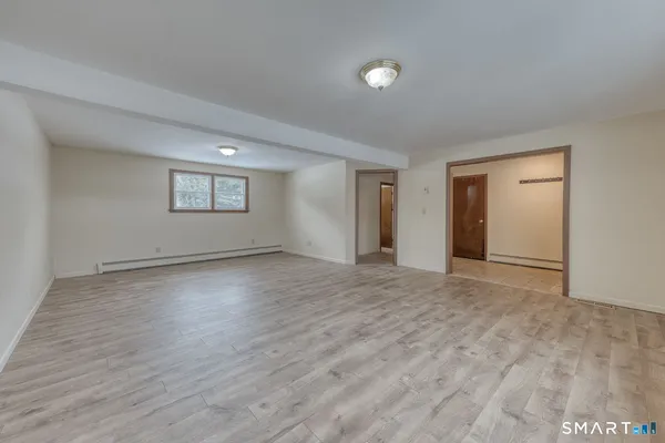 a view of an empty room with wooden floor and window
