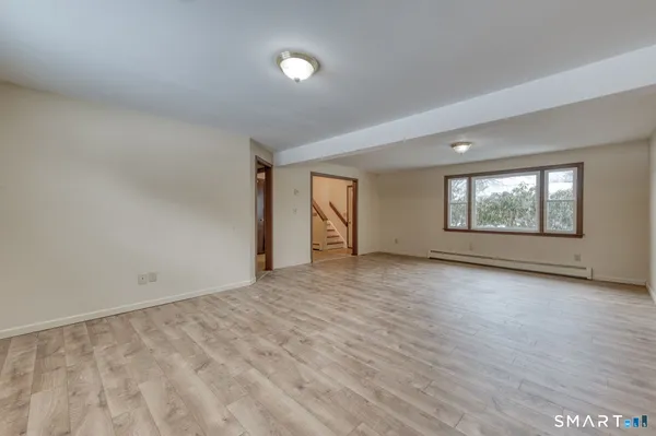 a view of an empty room with window and wooden floor